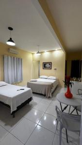 a hotel room with two beds and a table at The One Suíte in Monte das Gameleiras