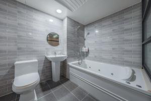 a bathroom with a white tub and a sink and a toilet at V Hotel in Gumi +54 photos