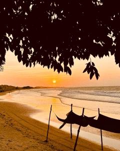 een hangmat op een strand met de zonsondergang op de achtergrond bij Casa Vento Curimãs in Barroquinha