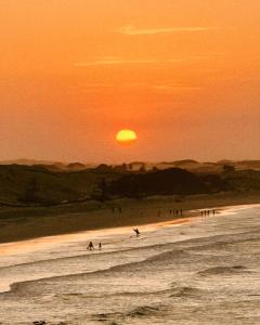 een groep mensen die bij zonsondergang op het strand surfen bij Casa Vento Curimãs in Barroquinha