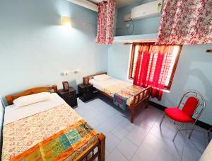 a room with two beds and a red chair at Saralalayam in Varkala