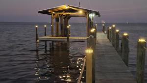 een dok met lichten op het water in de nacht bij Launch & Lounge in Titusville
