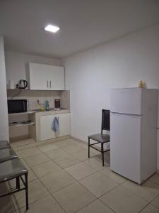 a kitchen with a white refrigerator and a table and chairs at Tres habitaciones Cómodo Residencia in Encarnación
