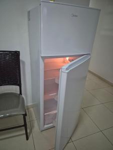 a white refrigerator with its door open next to a chair at Tres habitaciones Cómodo Residencia in Encarnación