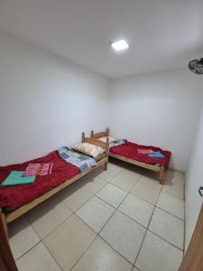 two beds in a room with a tile floor at Tres habitaciones Cómodo Residencia in Encarnación