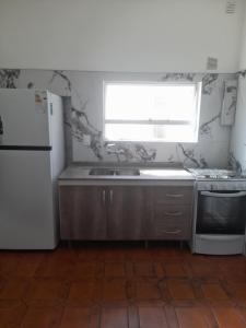 een keuken met een wastafel, een koelkast en een raam bij Complejo cardiel in Mar del Plata