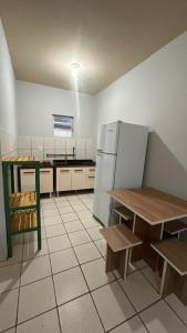 una cucina con frigorifero, tavolo e panche di Microcasa Nascimento a Imbituba