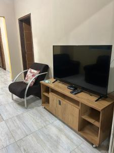 ein Wohnzimmer mit Flachbildfernseher und einem Sessel in der Unterkunft casa em peroba in Maragogi