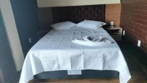 een bed met een wit dekbed erop bij Chalé com Piscina Aquecida - Vista Panorâmica da Praia, a 200m do Mar, Sala de Jogos, Academia e Churrasqueira in Imbituba +25 foto's