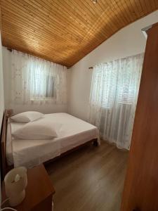 a bedroom with a bed and a window with white curtains at Apartments by the sea Prizba, Korcula - 149 in Prizba