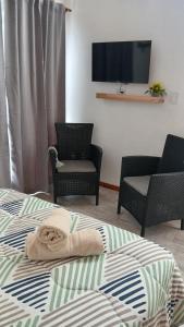 a bedroom with a bed with two chairs and a flat screen tv at Los Nenúfares in Lago Puelo