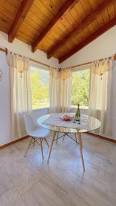 a table and a chair in a room with windows at Los Nenúfares in Lago Puelo