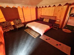 a bedroom with a bed and a couch in it at Palki Camps and Resorts in Kailāna +18 photos