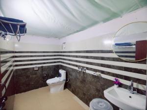 a bathroom with a sink and a toilet and a mirror at Palki Camps and Resorts in Kailāna