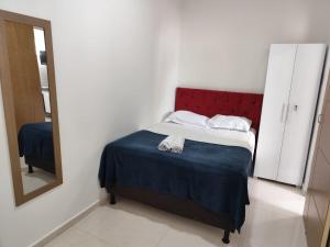 a bedroom with a bed with a red headboard and a mirror at Apartamento central - Feijó 01 in Vitória da Conquista