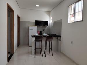 a kitchen with two bar stools and a refrigerator at Apartamento central - Feijó 01 in Vitória da Conquista