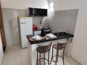 a kitchen with a counter with stools and a refrigerator at Apartamento central - Feijó 01 in Vitória da Conquista