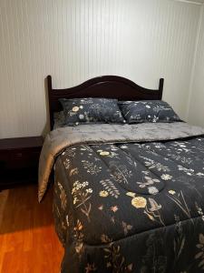 een bed met een zwart dekbed en kussens erop bij COMODA Y HERMOSA CABAÑA DE 2 dormitorios in Temuco