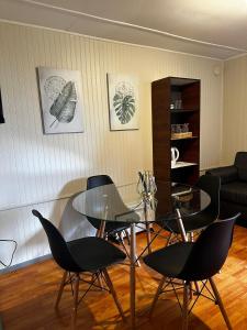 een woonkamer met een glazen tafel en stoelen bij COMODA Y HERMOSA CABAÑA DE 2 dormitorios in Temuco