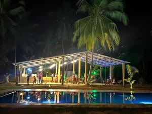 een groep mensen die 's nachts buiten een gebouw staan bij The Banana Cottage in Udawalawe