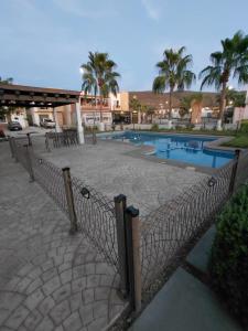 a fence in front of a swimming pool with palm trees at Casa privada Mediterráneo in La Paz