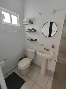 un bagno con un water, un lavandino e uno specchio di Casa en condominio Mediterráneo a La Paz Altre 6 foto