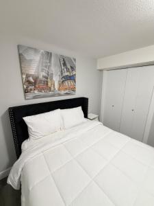 een slaapkamer met een wit bed met twee foto's aan de muur bij True Haven Deluxe in Prince George