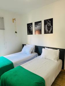 two beds in a room with pictures on the wall at Apartamento 4 quartos Contagem in Contagem