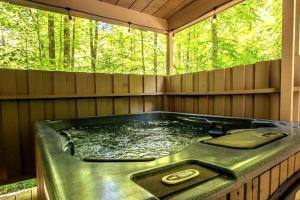 a jacuzzi tub in a room with two windows at BEES KNEES A-frame Cabin for 2 hot tub wifi in Gatlinburg