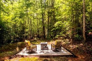 three chairs and a grill in the middle of a forest at BEES KNEES A-frame Cabin for 2 hot tub wifi in Gatlinburg