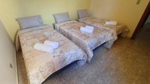 two beds in a room with white sheets at Casa amarela - Perto do Centro in Poços de Caldas