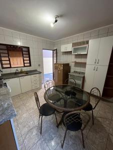 a kitchen with a glass table and chairs in a room at Casa amarela - Perto do Centro in Poços de Caldas