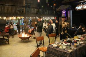 eine Gruppe von Menschen steht mit einem Teddybär um einen Tisch herum in der Unterkunft Pavi Lodge in Mèo Vạc