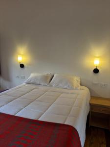 a bedroom with a bed with two lights on the wall at Lavanda lodge Ollantaytambo in Ollantaytambo
