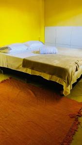 un grande letto in una stanza con parete gialla di Casa63 a Lençóis Altre 8 foto