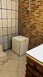 a small white refrigerator sitting in a room with a brick wall at Casa63 in Lençóis