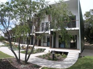 a white building with a tree in front of it at Frangipanis at Footprints in Preston Beach
