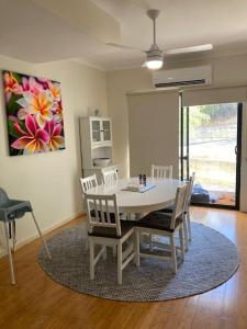 a dining room with a white table and chairs at Frangipanis at Footprints in Preston Beach