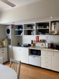 a kitchen with white cabinets and a table and a counter at Frangipanis at Footprints in Preston Beach +2 photos