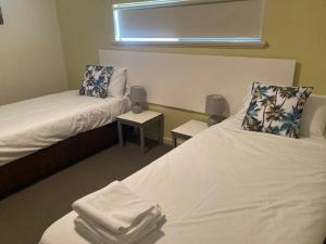 a room with two beds and two tables and a window at Frangipanis at Footprints in Preston Beach