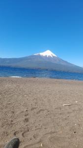 een persoon op een strand met een berg op de achtergrond bij Cabañas Loley - a pasos del lago in Puerto Varas