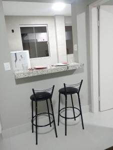 three black bar stools at a counter with a mirror at Conforto setor Oeste garagem 505 in Goiânia +14 photos