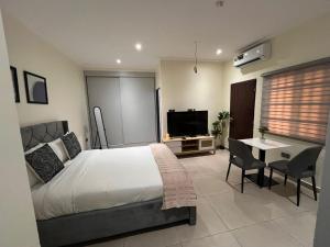 a bedroom with a bed and a table and a television at The Veron, Dzorwulu in Lapaz