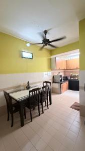 a kitchen with a table and chairs and a ceiling fan at Zuma Homestay in Sungai Buluh