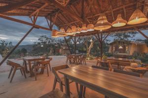 a restaurant with wooden tables and chairs and lights at Hotel Ambil in Barichara