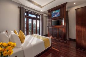 een slaapkamer met een wit bed met gele kussens en een tv bij Paradise Boutique Hoi An in Hội An