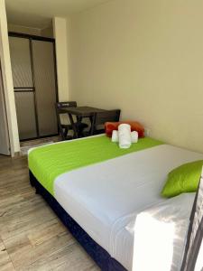 a bedroom with a bed with a green and white blanket at Best View Aparta Hotel in Dosquebradas