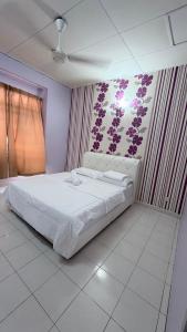 a bedroom with a white bed with a wall with purple flowers at Zuma Homestay in Sungai Buluh