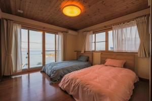 a bedroom with two beds and a large window at さざなみハウス熱海 in Atami