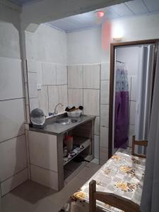 een kleine keuken met een wastafel en een tafel bij Kitinete Quarto para casal in Matinhos